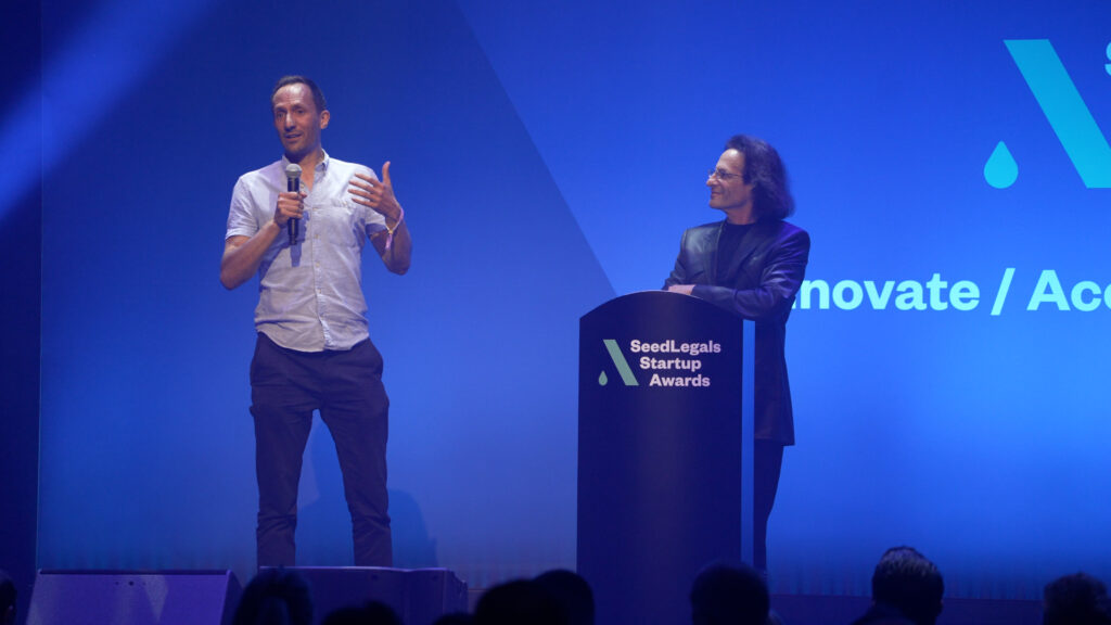SeedLegals CEO Anthony Rose standing on stage next to The Pitch founder Chris Goodfellow at the SeedLegals Awards 2025.